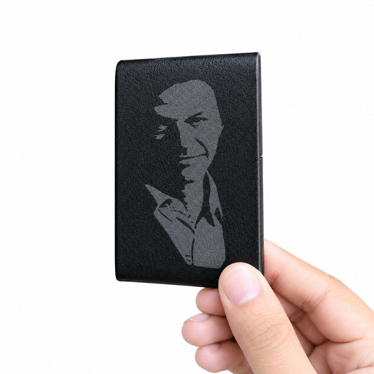 A hand holding a black textured leather card holder or wallet featuring a debossed gray portrait of a man, shown against a plain white background.