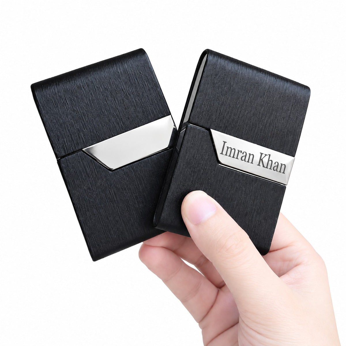 Hand holding the pair of slim black leather card holders highlighting their lightweight and compact design.
