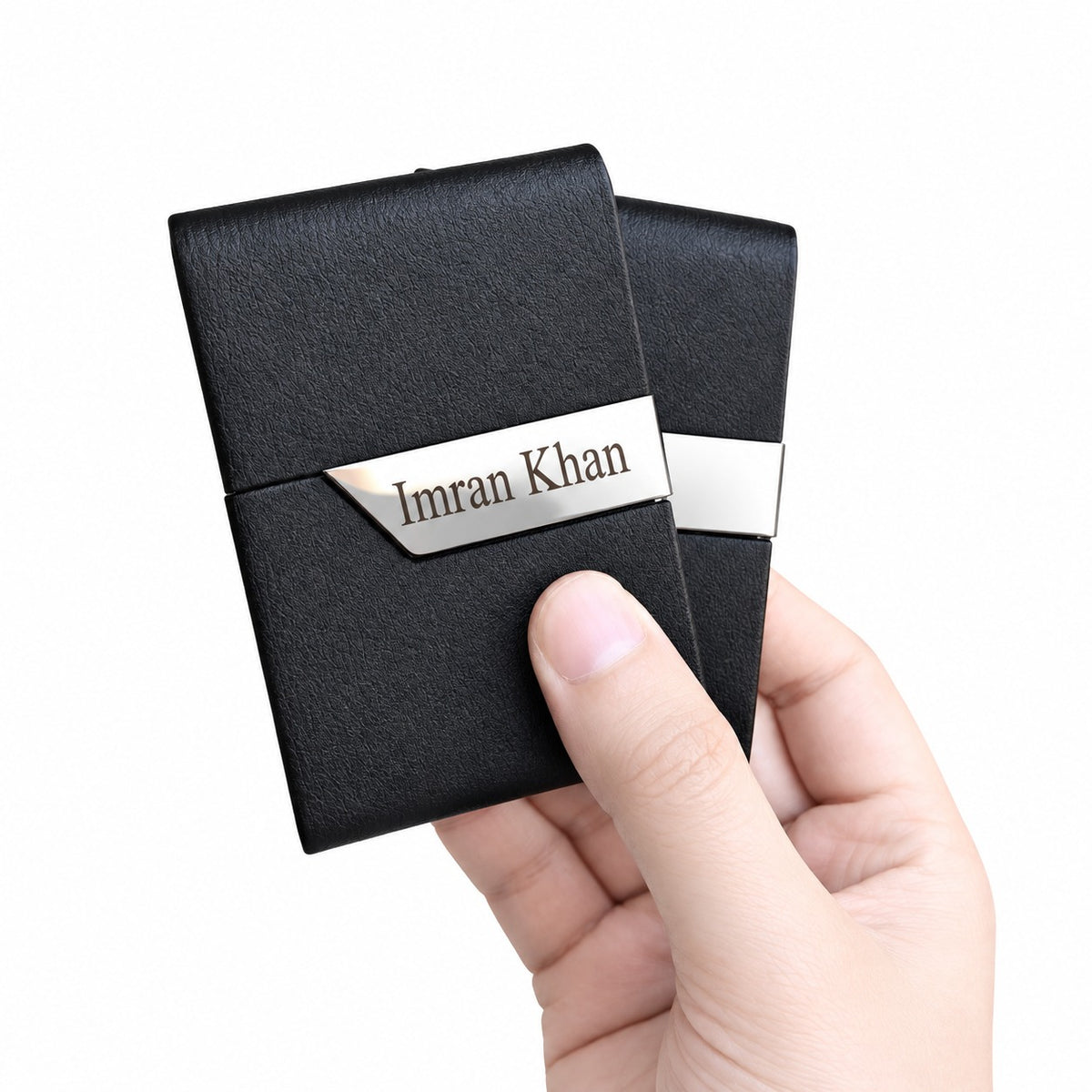 Hand holding the pair of slim black leather card holders highlighting their lightweight and compact design.