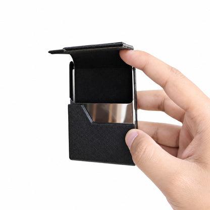 Minimalist black leather and metal card holder held in hand, demonstrating its compact and lightweight pocket-sized design.